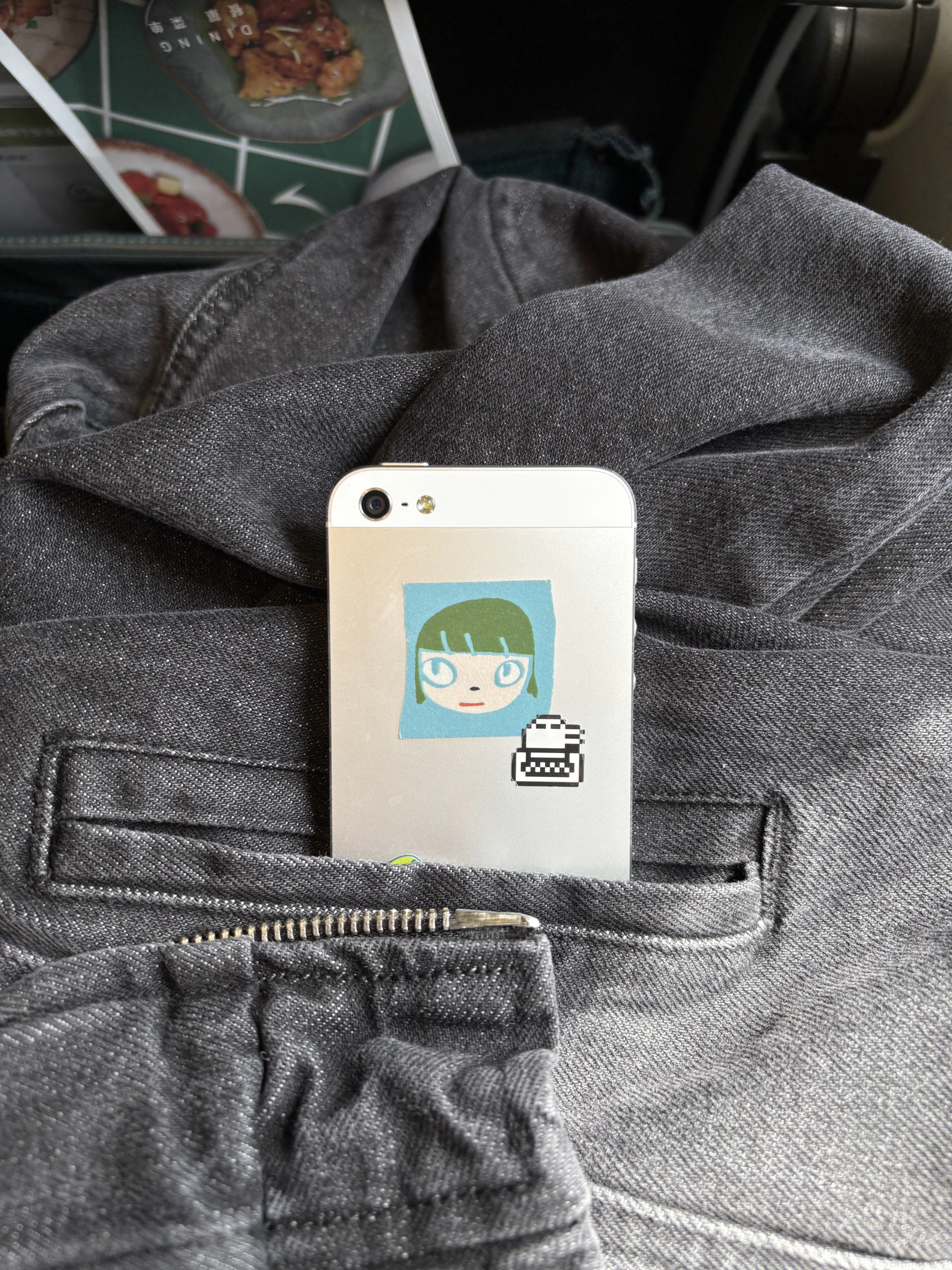 An iPhone 5 tucked into the pocket of a denim jacket
